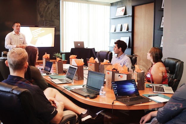 People gathered around a table with laptops, engaged in discussions to foster a culture of learning and knowledge sharing.